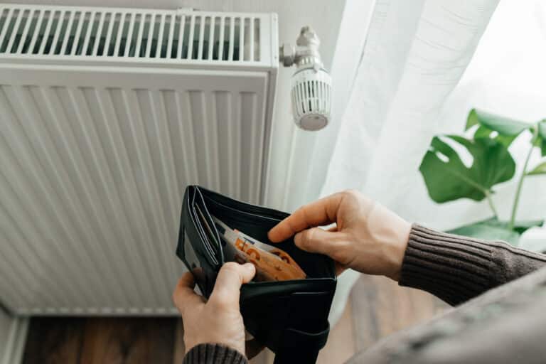 the man's hands hold a wallet with money next to the radiators. the concept of increasing prices for gas and energy. energy crisis in europe.