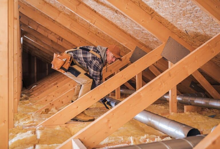 male contractor installs metal pipe system in attic.