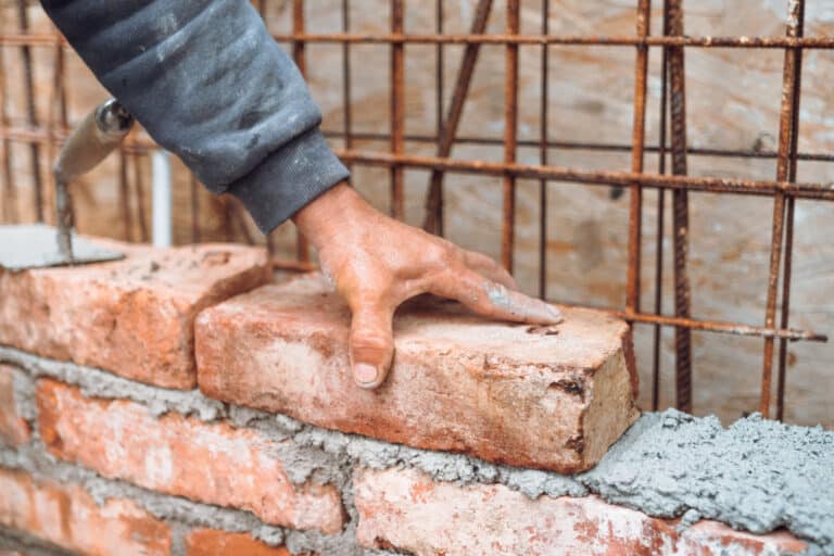 details of worker, bricklayer placing and adjusting bricks. professional construction worker building exterior walls